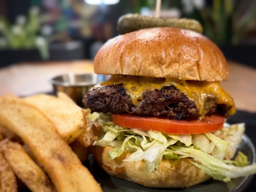The Highlander Burger with aged cheddar, shredded iceberg, tomato, and onion marmalade, served with potato wedges at Maisie&rsquo;s Green Brae in Tega Cay